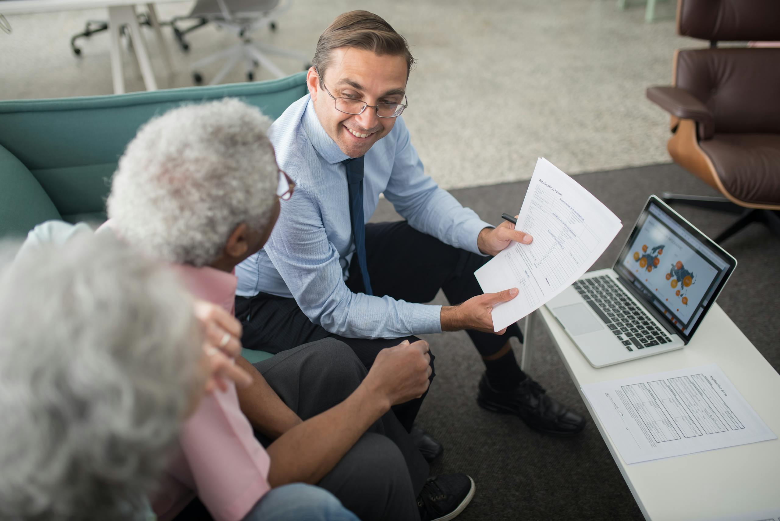 Financial advisor discussing documents with senior clients in an office setting, showcasing a collaborative consulting session.