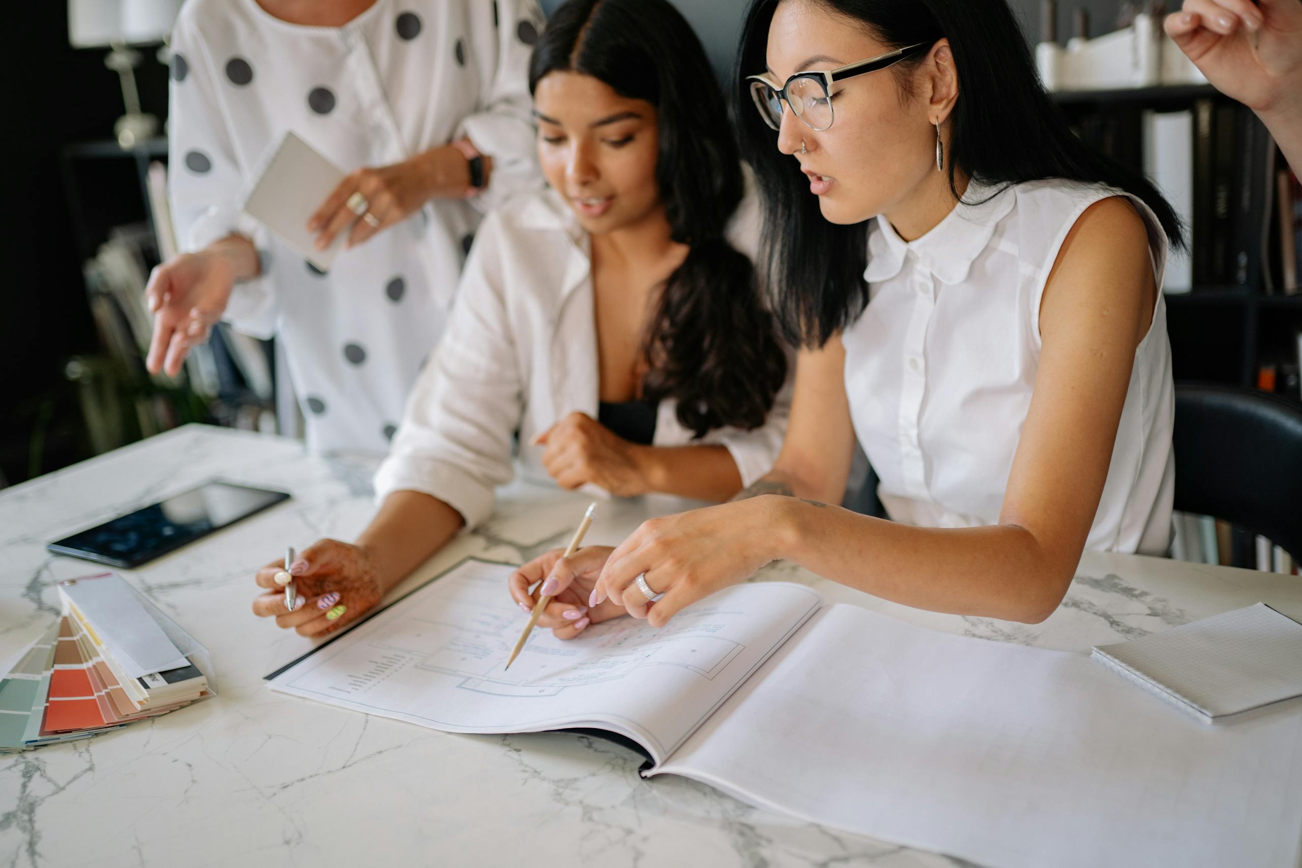 Professional women discussing project details during a collaborative office meeting.